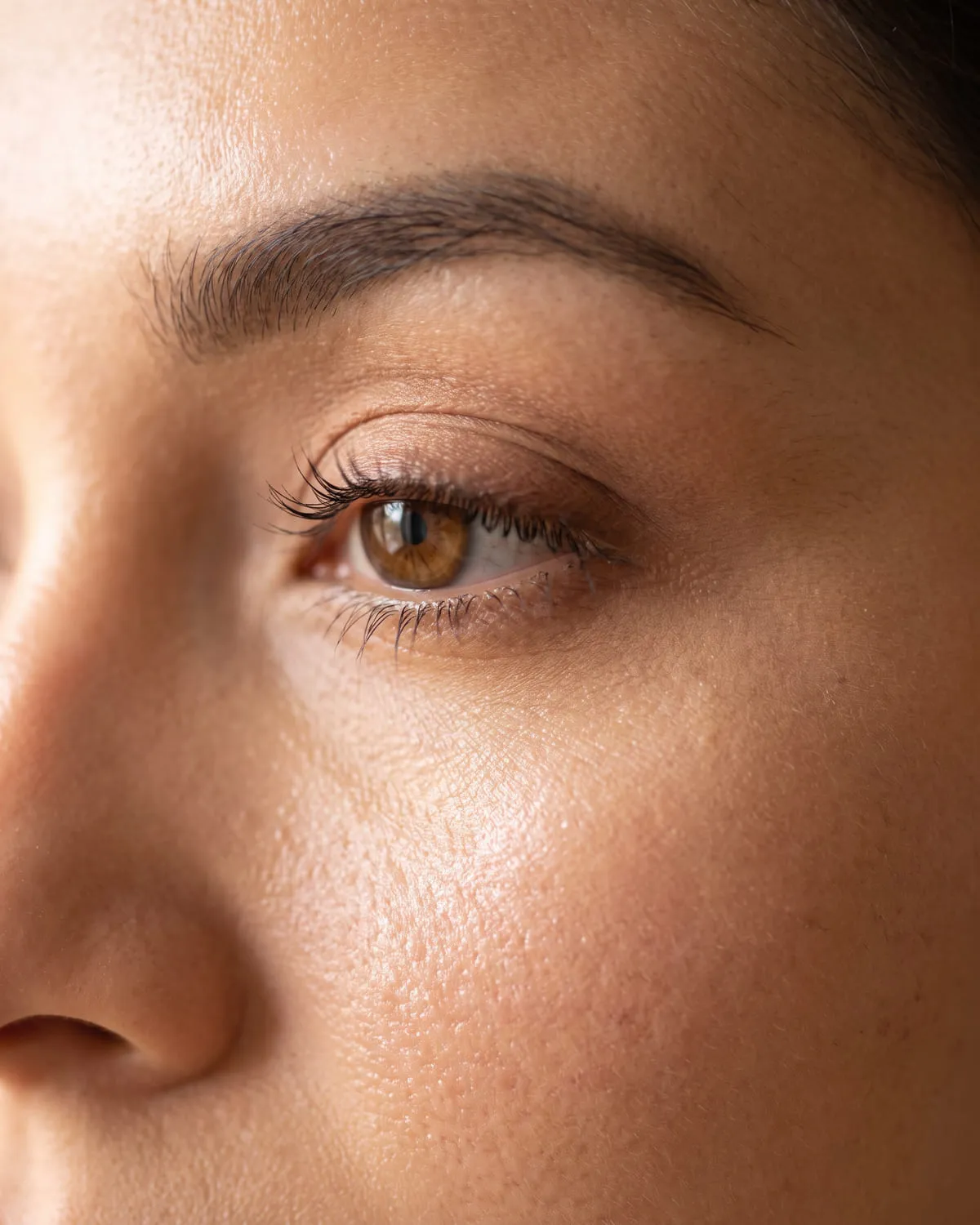 Detalle cercano de un ojo con maquillaje social en tonos cálidos y las pestañas definidas