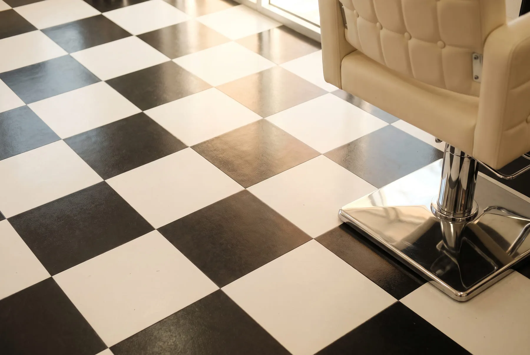 Detalle del piso de damero negro y blanco del salón, con la base cromada cuadrada de un sillón